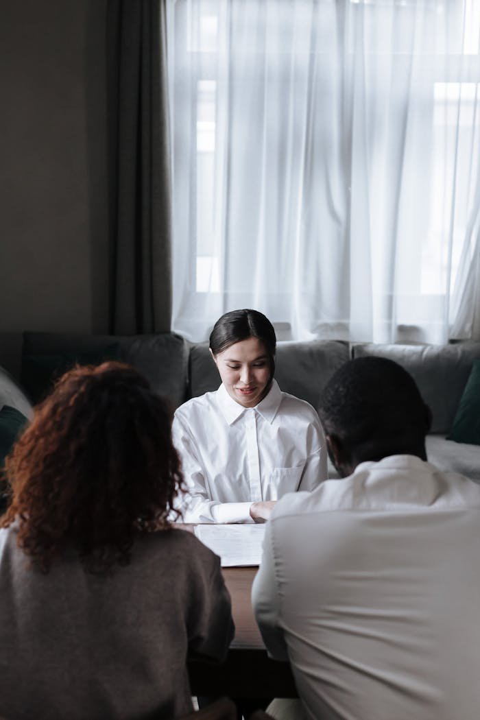 A diverse group meeting with a social worker in a cozy home setting, discussing important documents.